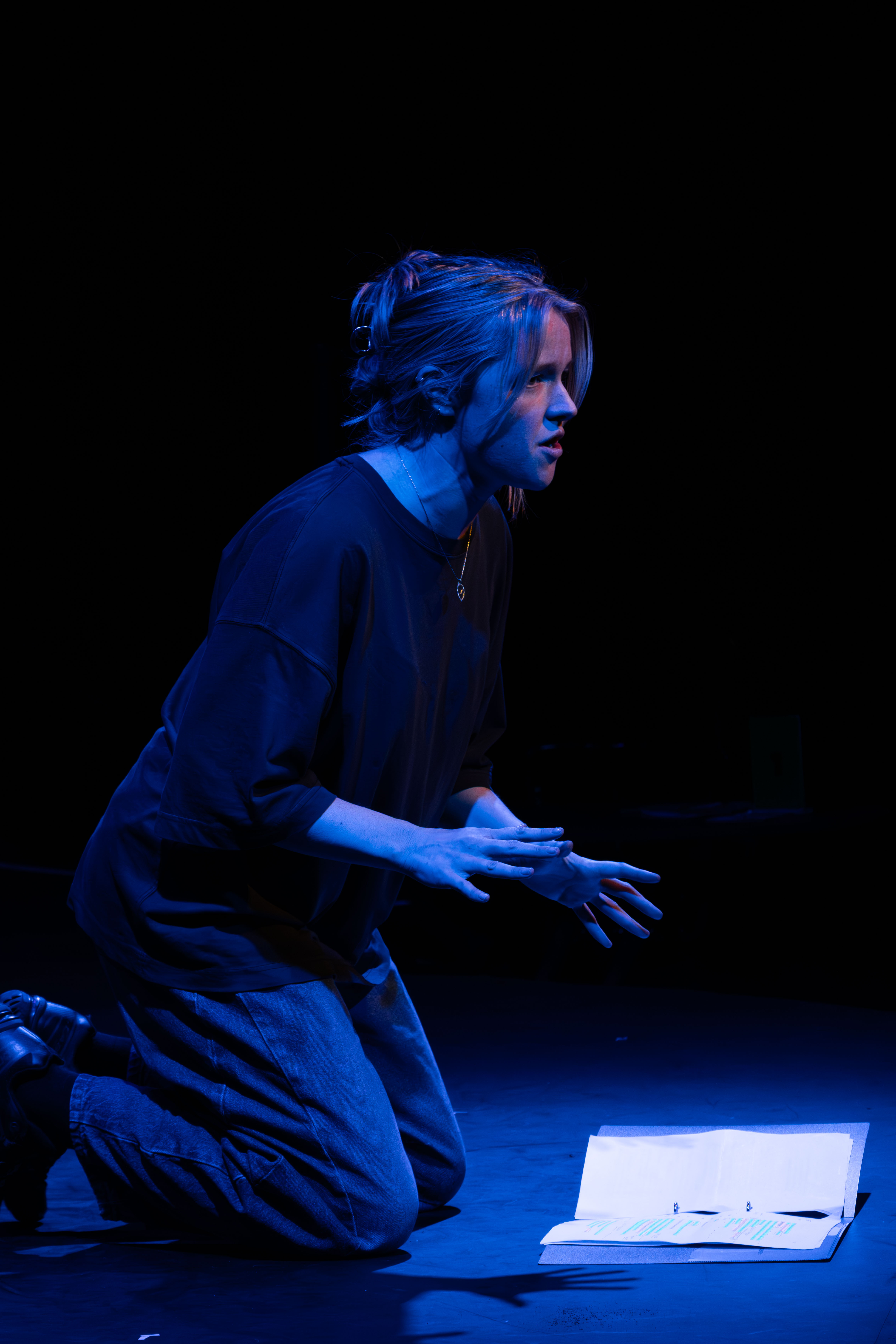 Liv onstage as Mag, knelt down. Blue light.