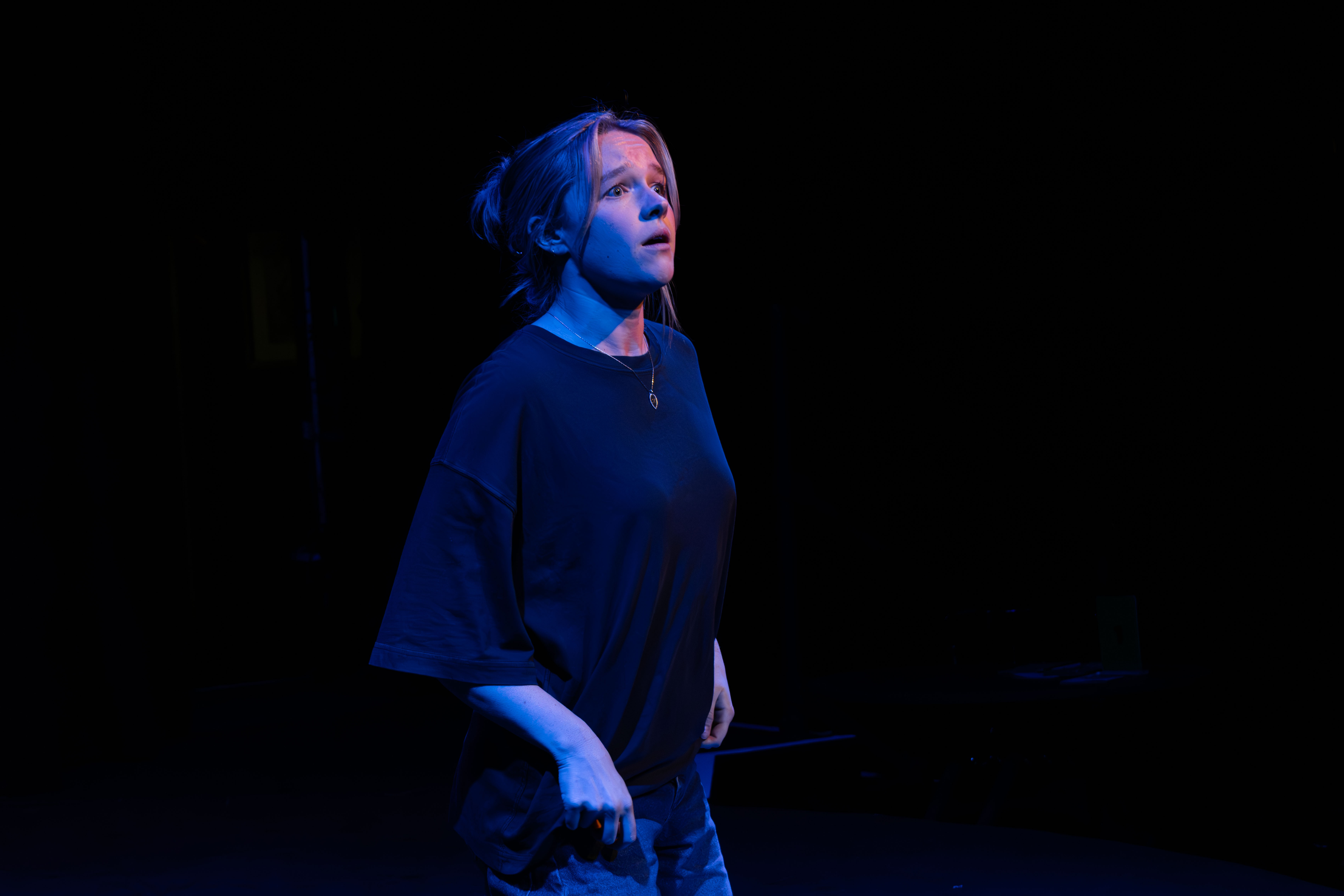 Liv onstage as Mag, looking up. Blue light.