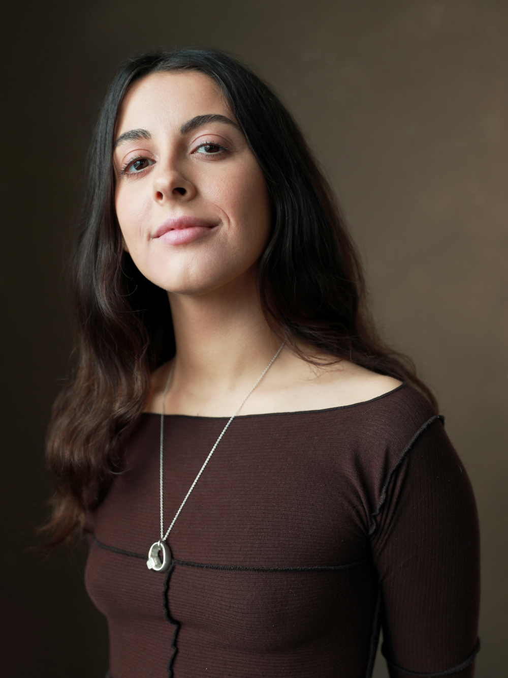 A headshot of Kayleigh wearing a brown top, looking at the camera.