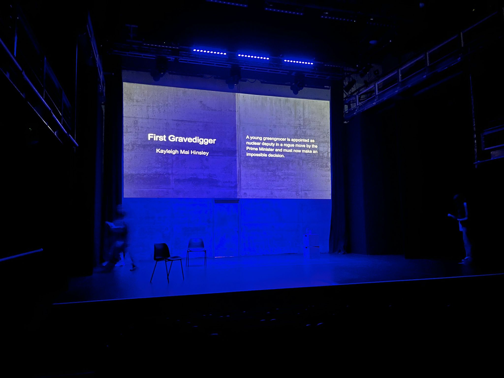 Projected text of the title and logline onstage at the Belgrade.