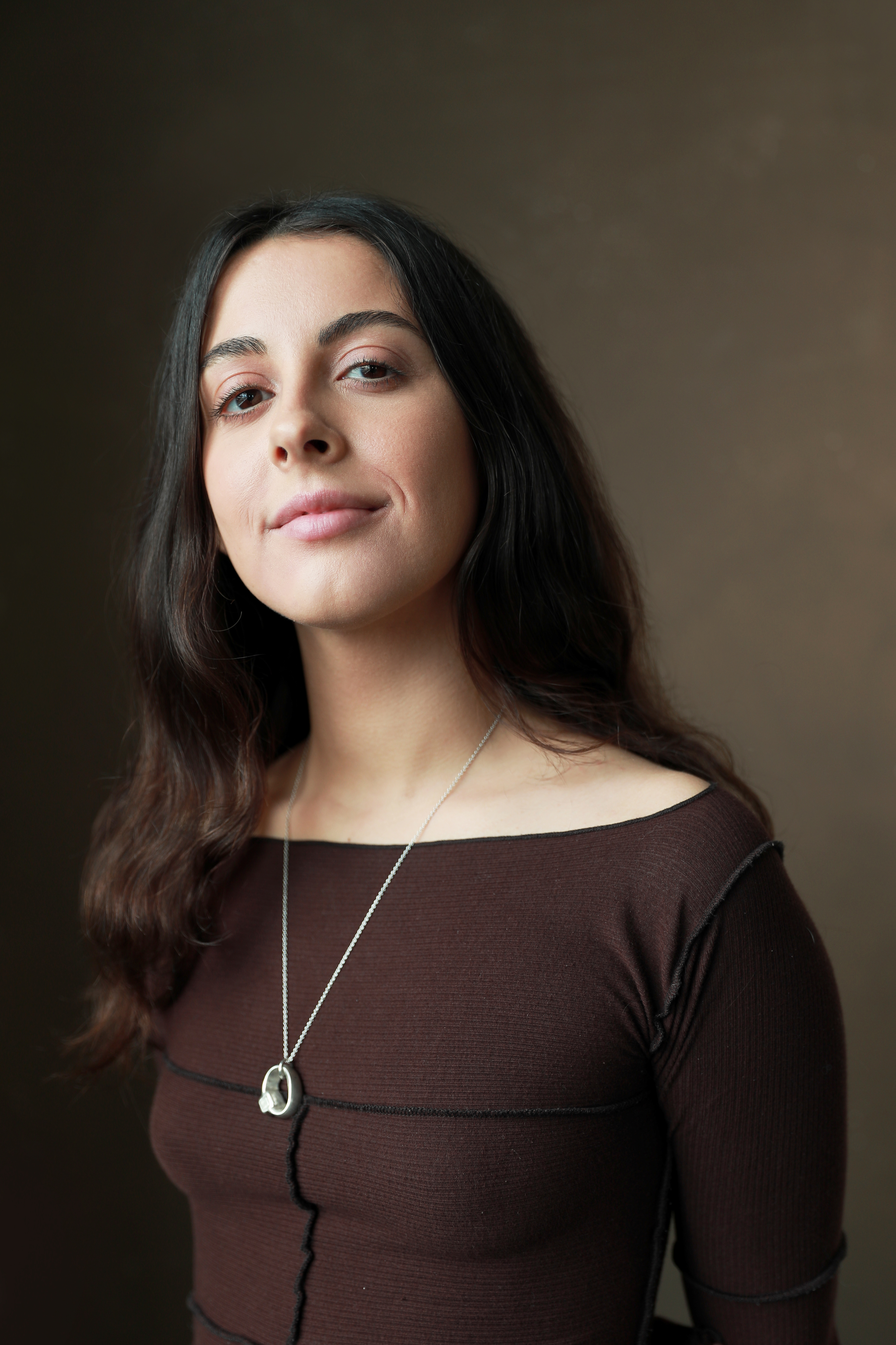 A headshot of Kayleigh wearing a brown top, looking at the camera.